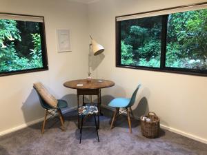 a table and chairs in a room with two windows at Tranquil Studio in New Plymouth