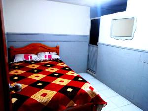 a bedroom with a bed with a red and black quilt at Hotel NEFER in Pasto