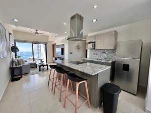 a kitchen with a island with bar stools and a refrigerator at Altomare hermoso depa con vista al mar in Mazatlán