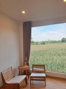 a room with two chairs and a large window with a field at The FAITH Khaoyai Valley in Ban Rai Khlong Sai