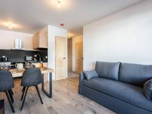 ein Wohnzimmer mit einer blauen Couch und einer Küche in der Unterkunft Neuf T2 avec balcon, parking et casier à skis, idéal pour 4 personnes - FR-1-291-1021 in Valmorel