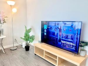 a flat screen tv sitting on a wooden stand in a living room at Spacious & Comfy Upper Floor 3BR Suite in Detached House in Calgary +32 photos
