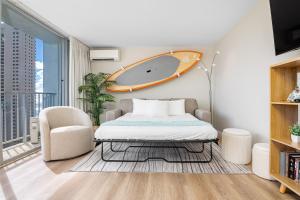 a bedroom with a bed and a surfboard on the wall at Stylish Studio with Great Ocean Views & Near Beach! in Honolulu