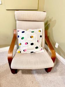 una silla con una almohada de lunares. en Cozy Walkout suite with King bed, Kitchen, Parking & Patio, en Calgary