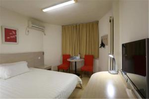 a hotel room with a bed and a flat screen tv at Jinjiang Inn Qingdao Bus Station in Qingdao