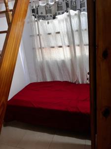 a bedroom with a red bed and a window at DuplexNico in Santa Teresita +4 photos