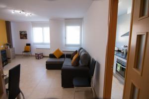 a living room with a black couch and a kitchen at Apartament Bagà in Bagá