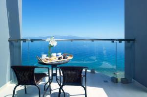 een tafel en stoelen op een balkon met uitzicht op het water bij Arion Hotel in Xylokastron