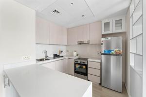 a kitchen with white cabinets and a stainless steel refrigerator at Silkhaus Canalside 1BR at Water's Edge in Yas Island in Abu Dhabi +13 photos