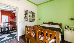 a bedroom with a bed with green walls and chairs at The Corner Courtyard in Kolkata