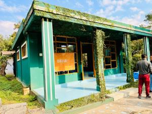 a man standing in front of a green building at Cozyo Stays Boutique Home Jowai in Jowai