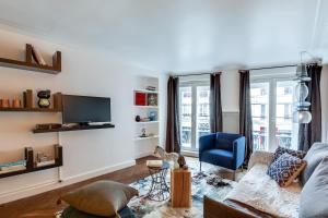 a living room with a couch and a tv at Sweet Inn - Etienne Marcel in Paris
