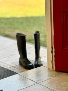 Green Acres Farm Cottage في Ritchie: اثنين من الأحذية المطاطية السوداء كانوا يجلسون على الشرفة