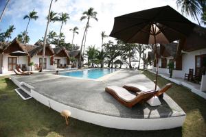 a pool with two lounge chairs and an umbrella at Elysia Beach Resort in Donsol