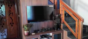 a flat screen tv on a wooden entertainment center at Bettadakeshvi homestay in Belūr