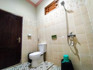 a bathroom with a toilet and a shower at Famoris Cottages in Tetebatu