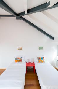 two beds in a room with a red table at FLH Bairro Alto Luxus Flat in Lisbon