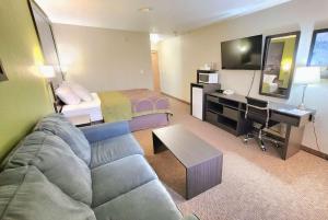 Super 8 by Wyndham Portage La Prairie MB في بورتاج لا بريري: غرفة فندق مع أريكة وسرير