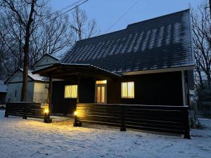 a black house with lights in the snow at コテージソラ まるっと一棟貸切り別荘 in Nasu-yumoto
