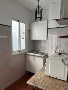 a kitchen with white cabinets and a sink and a window at Casa Puente ROMANO cerca de Sevilla in Alcalá de Guadaira