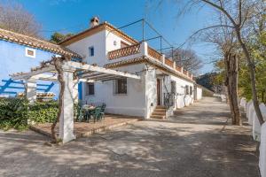 une maison blanche avec une pergola devant elle dans l'établissement Apartamento El Tinao, à La Zubia