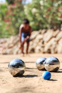 three metal balls on the ground with a person in the background at Hotel Club Le Capet in Sainte-Maxime