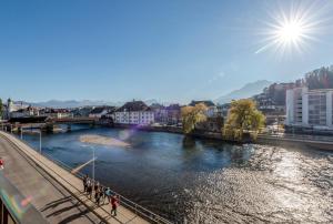 a river in a city with people walking on a bridge at Boutique Hotel KARL in Lucerne