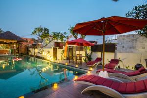 una piscina con sillas y sombrillas junto a ella en Jay's Villa Umalas, en Canggu