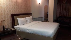 ein Schlafzimmer mit einem großen Bett mit weißen Laken und Kissen in der Unterkunft Ambassador Inn in Islamabad + 5 Fotos