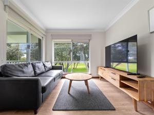 a living room with a couch and a tv at Mandalay Holiday Resort and Tourist Park in Busselton