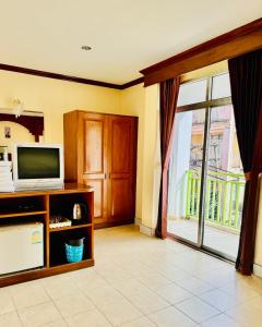 un salon avec une télévision et une grande fenêtre dans l'établissement Innarm House Patong, à Patong Beach