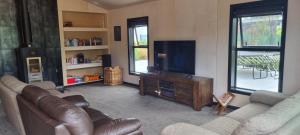 a living room with couches and a flat screen tv at Lake Opuha House in Ashwick Flat