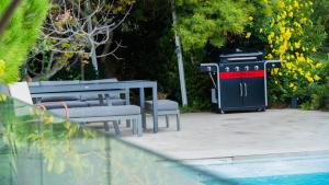 dwie ławki i kosz na śmieci obok basenu w obiekcie Belle villa provençale avec piscine privée w mieście Carqueiranne