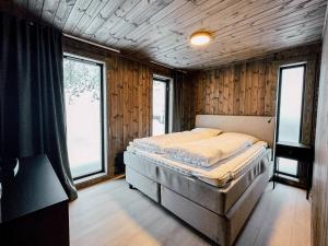 a bedroom with a bed in a room with windows at Modern Mountain Cabin - 3 Bedrooms - Sleeps 7 in Torpo