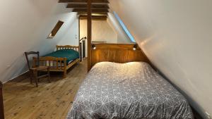 a attic room with a bed and a chair at Charmante maison de village in Condat-sur-Vézère