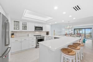 a kitchen with white cabinets and a large island with stools at Sanddollar #A202 in Ybel