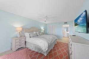 a white bedroom with a bed and a tv at Sanddollar #A202 in Ybel