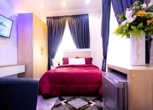 a bedroom with a red bed and a vase of flowers at Firnic Luxurious Private Hotel in Accra