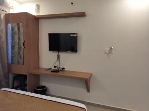 a room with a tv on a wall with a desk at CLASSIC COMFORT Lodge in Mangalore
