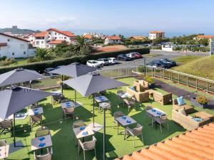 een uitzicht op tafels en stoelen met parasols bij ibis Styles Biarritz Plage in Biarritz
