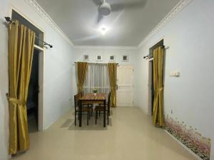 a dining room with a table and yellow curtains at Himawari House in Batam Center