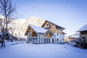 una casa en la nieve con una montaña en el fondo en Chalet Le Strato, en Valloire