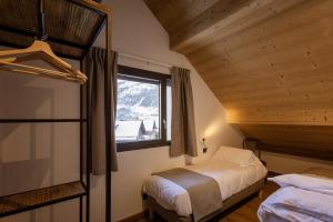 Un dormitorio con dos camas y una ventana. en Chalet Le Strato, en Valloire