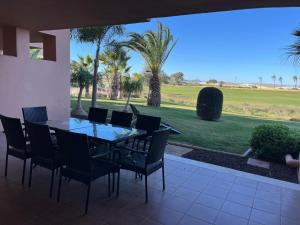 a dining room table with chairs and a view of a golf course at Beautiful 2 Bed Apartment Mar Menor Golf Resort in Los Martínez