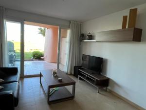 a living room with a couch and a tv and a table at Beautiful 2 Bed Apartment Mar Menor Golf Resort in Los Martínez