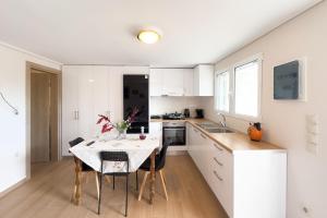 アルテミダにあるElena's Home Apt 1の白いキャビネットとテーブルと椅子のあるキッチン +17枚の写真
