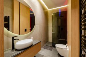 a bathroom with a sink and a toilet and a mirror at LupoApartments z Klimatyzacją do wyboru z Jacuzzi Pole Dance Parking Dostęp na Kod in Łódź