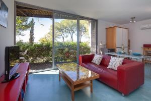 Una sala de estar con un sofá rojo y una mesa. en Apartment in the heart of nature near Seville with swimming pool and parking, en Espartinas