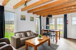 a living room with a couch and a table at Sfeervolle Zeeuwse Cottage met extra slaapkamer 4 personen in Wemeldinge