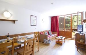 una sala de estar con una mesa y un sofá en Résidence Odalys Les Hauts du Rogoney, en Val dʼIsère